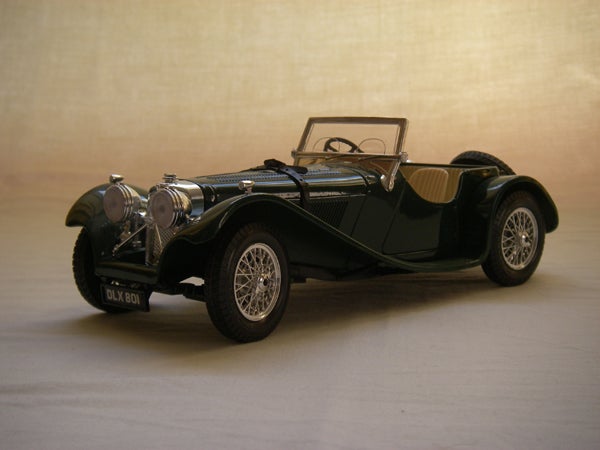 Classic black vintage car model with detailed design and clear headlights on a beige background.
