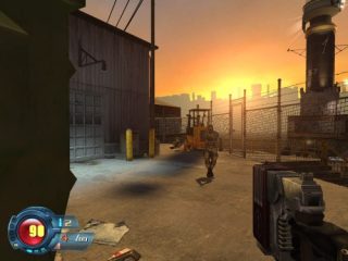 First-person perspective screenshot from the video game Sin Episodes: Emergence showing a player character holding a gun with a health and ammo HUD display, ready for combat in an industrial outdoor setting with a sunset sky in the background.