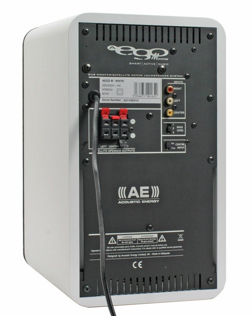 Rear view of an Acoustic Energy Aego M subwoofer showing various input connections, power switch, and volume control, with a power cable plugged in. The white casing contrasts with the black back panel which features the brand logo and model information.