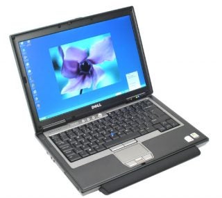 Dell Latitude D620 laptop with screen displaying a flower wallpaper, the device is open showcasing the keyboard and touchpad.