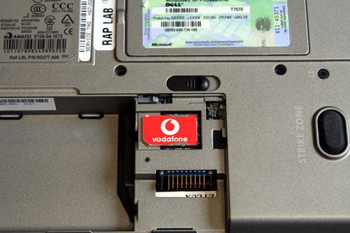 Dell Latitude D620 laptop with the battery compartment open showing a Vodafone mobile broadband card inserted into the slot.