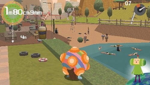 Screenshot from the video game 'Me and My Katamari' showing gameplay where the player-character is pushing a colorful Katamari ball in a park-like environment with various objects and people that can be rolled up to increase the size of the ball.