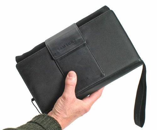 A hand holding a Samsung Q1 Ultra Mobile PC in a black protective case with a wrist strap.
