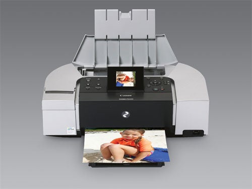 Canon PIXMA iP6220D printer with output tray extended, printing a color photo of a girl sitting on the beach, set against a neutral gray background.
