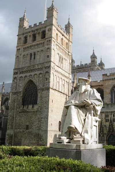 Statue in front of an ornate historical building with towers and arched windows.