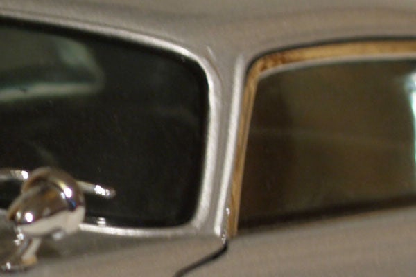 Close-up of a tarnished and dirty car window frame with a focus on corrosion and wear near the seal.