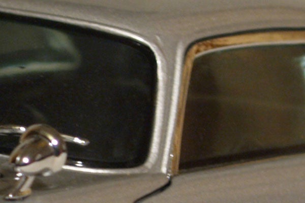 Close-up of a silver car's side mirror and window detail with reflections visible.