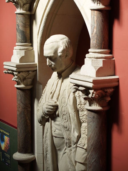 Statue of a historical figure displayed in an architectural alcove with decorative columns.