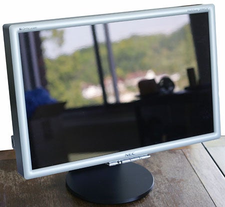 NEC MultiSync 20WGX2 20.1-inch widescreen LCD monitor with a glossy screen, displayed on a desk with reflection visible on the screen and a blurred background.