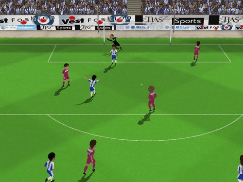 Screenshot of Sensible Soccer 2006 gameplay showing a football match with players in blue and pink jerseys on the pitch, a view towards the goalpost, and advertisement boards in the background.