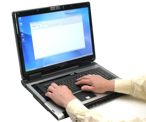 A person using an Acer Aspire 9800 20-inch Notebook with an open word processor on the screen.
