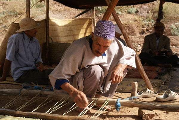 Man weaving on a traditional loom outdoors