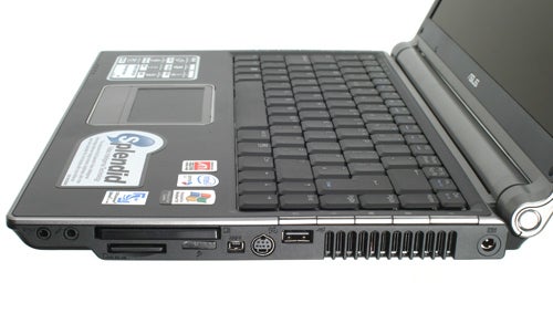 Asus W3J 14-inch dual-core notebook with the lid open, showing the keyboard and the left side ports which include USB, VGA, and Ethernet connections. The laptop has several stickers, including Intel Centrino Duo branding, on its palm rest area.