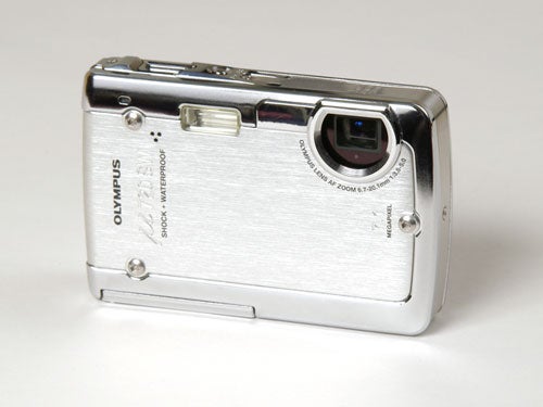 Olympus µ 720SW rugged digital camera sitting on a white surface, showcasing its silver body and lens on the front side.
