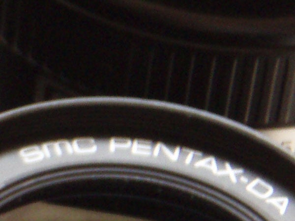 Close-up of a Pentax camera lens with visible branding and model details.