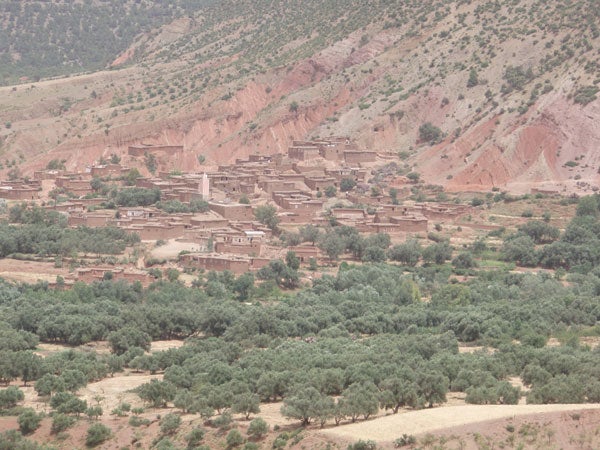 Photograph taken with an Olympus µ 720SW rugged digital camera showcasing a rural village nestled in a green valley with olive trees in the foreground and arid hills in the background.