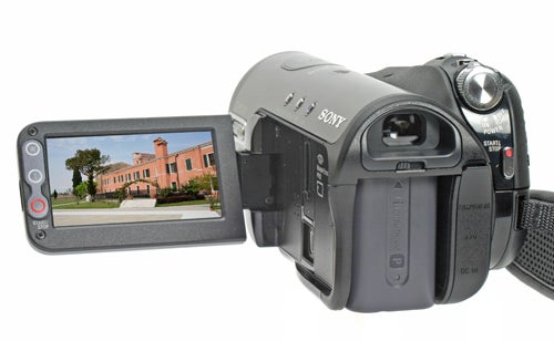 Sony HDR-HC3E HD Camcorder with flip-out LCD screen displaying a building, focus on the camera's right side showing ports and buttons, isolated on a white background.