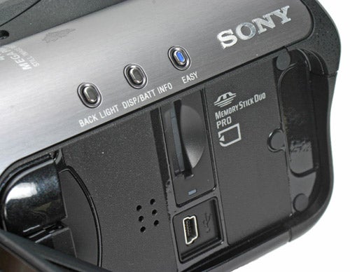 Close-up of a Sony HDR-HC3E HD Camcorder showing the button layout including options for backlight, display, battery info, and an easy mode, with a Memory Stick Duo PRO card slot visible.