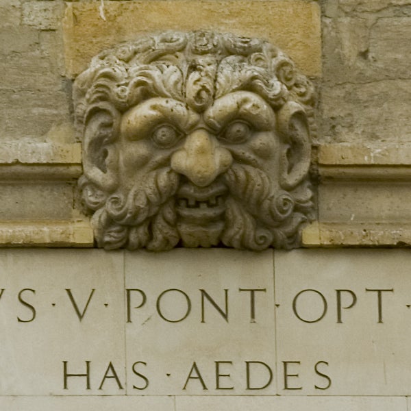 This image does not correspond with a Nikon D200 - Digital SLR product review. It is a close-up photograph of a sculpted stone face with intricate details, possibly part of a historical building or monument, with engraved Latin text below it.