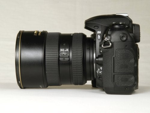 Nikon D200 digital SLR camera with a black lens attached, shown from the side on a light background.