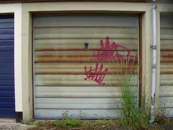 Rusty metal garage door with pink graffiti.