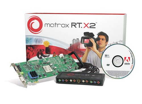 Matrox RT.X2 video editing hardware with breakout box, PCI card, and Adobe software CD displayed in front of its packaging box featuring the product name and an image of a person holding a camera.