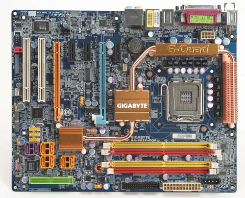 Gigabyte GA-965P-DQ6 Core 2 Duo motherboard with blue PCB, copper heatpipes, and multiple color-coded connectors and slots visible.