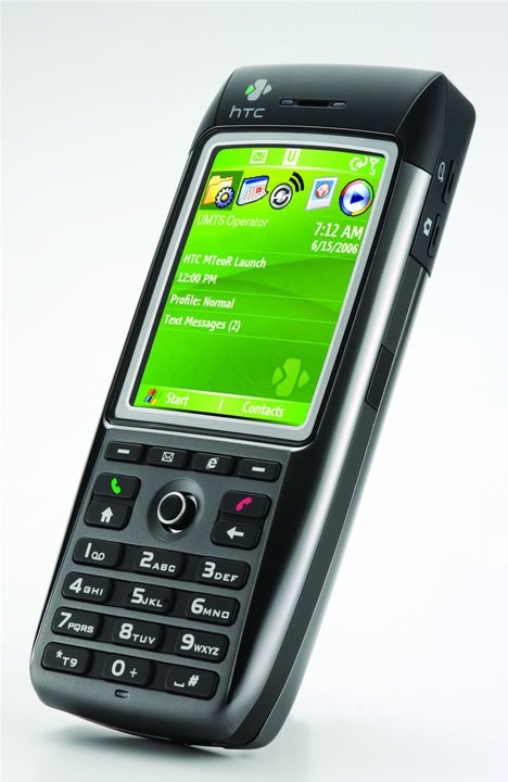 HTC MTeoR Windows Mobile 3G smartphone featuring a QVGA display with a home screen showing icons for applications and date, a black keypad with navigation controls, and branding on a white background.