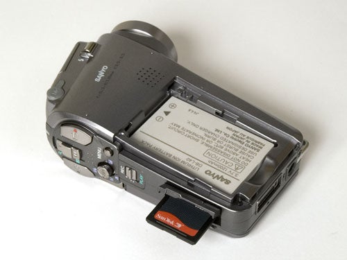 Sanyo Xacti VPC-HD1 camcorder with the battery compartment open and an SD card partially inserted, displayed on a neutral background.