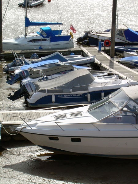 Photograph taken with a Nikon Coolpix L4 showing a variety of boats docked on a dry riverbed, with sunlight reflecting off the water in the background.