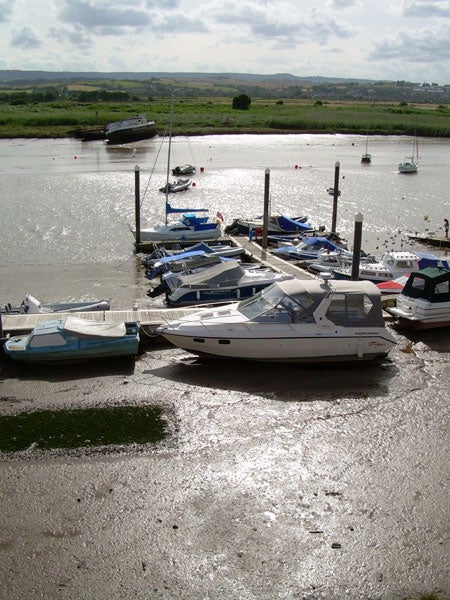 A photograph taken with the Nikon Coolpix L4 showing a variety of boats, including sailboats and motorboats, moored in a tidal area with water and mudflats under a partly cloudy sky.