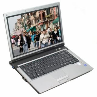 Samsung X11 Dual-Core Notebook open on a white background displaying a colorful street scene on its screen.