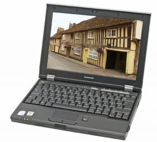 Lenovo 3000 V100 Ultra Portable Notebook open on a desk displaying a picturesque old town on the screen with the brand's logo visible below the display.