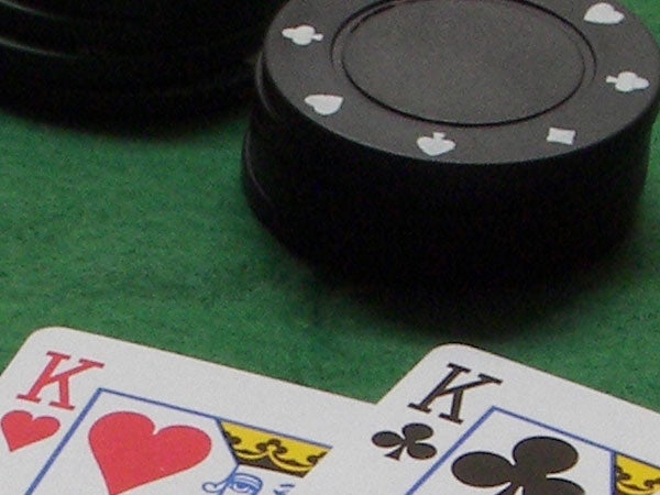 Close-up image of a pair of kings in a hand of cards with poker chips in the background on a green felt surface.