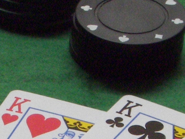 Close-up photo of playing cards showcasing the King of Hearts and a corner of the King of Clubs, with out-of-focus black poker chips in the background, indicating a shallow depth of field likely captured with a Kodak EasyShare P712 camera.