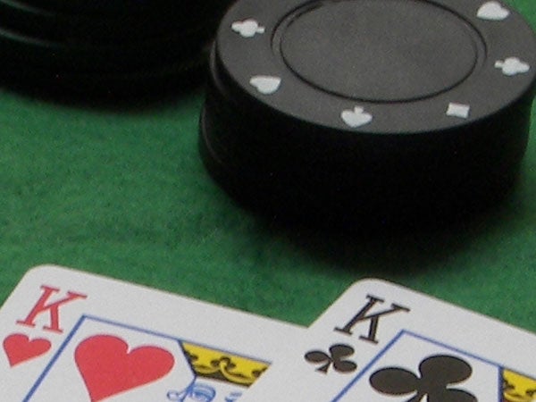Poker game close-up showing two kings with casino chips on a green felt table.
