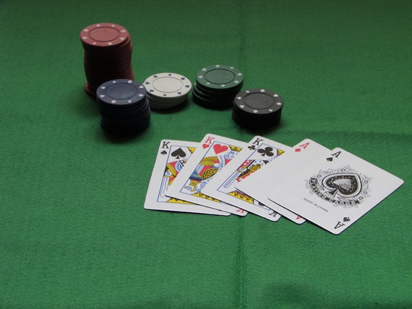 A royal flush in spades displayed on a green surface with multiple stacks of poker chips in black, red, white, and green colors.Poker game close-up showing two kings with casino chips on a green felt table.