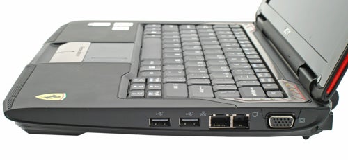 Acer Ferrari 1000 laptop placed on a flat surface featuring the Ferrari logo, showcasing the keyboard and the right side ports including USB, Ethernet, and VGA connectors.