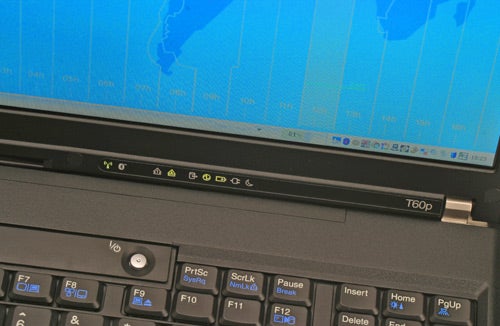 Close-up of Lenovo IBM ThinkPad T60p laptop keyboard with a focus on the model number badge, set against a blurred screen displaying a blue graph.
