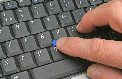Close-up of a person using the pointing stick on a Dell Latitude D420 laptop keyboard.