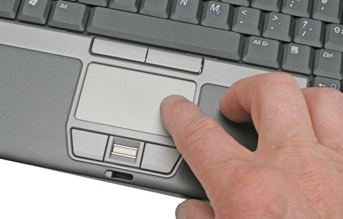 Close-up of a hand using the touchpad on a Dell Latitude D420 laptop.