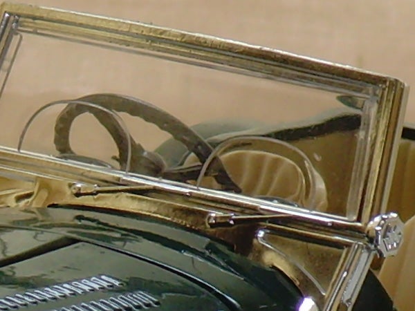 Close-up photo of a vintage car's windshield and steering wheel.
