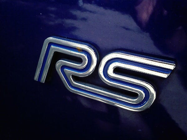 Chrome 'RS' badge on a dark blue automotive surface.