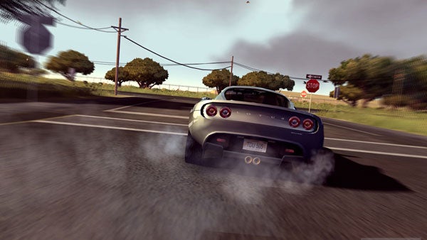 Screenshot from the video game Test Drive Unlimited showing a silver sports car performing a burnout on an asphalt road with a STOP sign in the background.