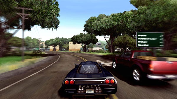 In-game screenshot from Test Drive Unlimited showing a first-person perspective from behind the wheel of a black sports car driving on a paved road with lush greenery on either side, overtaking a red truck, with direction signs and competitor names displayed on the top left.