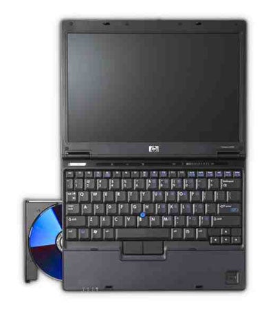 HP Compaq nc2400 Ultra-Portable Notebook open at a 90-degree angle, showcasing the keyboard layout, display screen, and touchpad, with a CD partially ejected from the side-mounted optical drive.