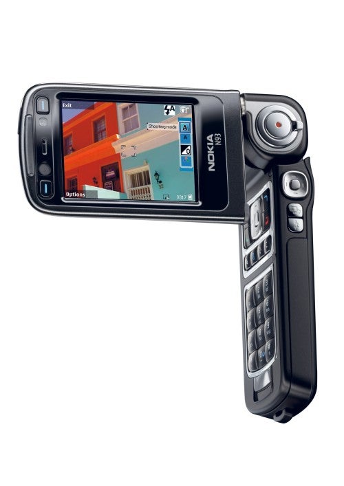 Nokia N93 phone with the screen rotated and camera extended, displaying camera interface on screen with a room in the background.