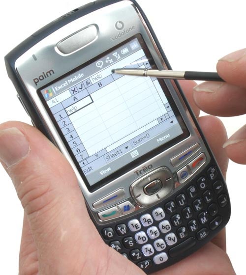 Hand holding a Palm Treo 750v smartphone with a stylus interacting with a spreadsheet application on the screen.