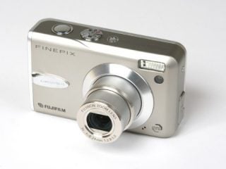 Fujifilm Finepix F30 compact digital camera on a white background, featuring silver casing, extended zoom lens, and built-in flash.