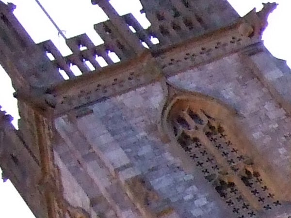 Blurry image of a historic stone building with Gothic architecture details, possibly taken in low light conditions or with camera shake, demonstrating a potential quality issue or user error.